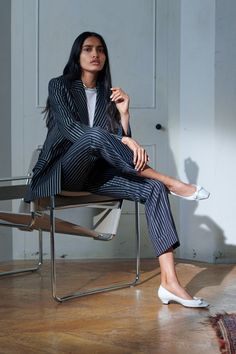 a woman sitting in a chair with her legs crossed and one foot up on the ground