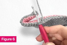 someone crocheting the end of a piece of yarn with a red handled crochet hook