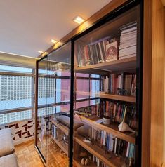 the bookshelves in this room are full of books and have glass doors to let in light