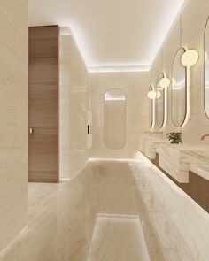 a bathroom with marble walls and flooring, mirrors on the wall, and lights hanging from the ceiling