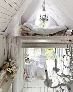 two beds in a room with white walls and flooring, one has a chandelier hanging from the ceiling