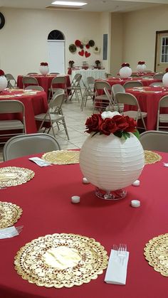 a red table topped with lots of white plates covered in paper flowers and gold trimmings