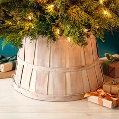 a christmas tree in a wooden bucket with presents under it and lights on the top