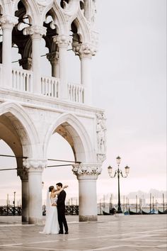 a bride and groom are standing in front of an ornate building with arches on the sides