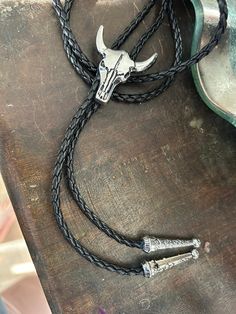 This awesome bolo tie has a steer skull design. Real leather cord. Quality guaranteed, picture does not do this buckle justice!    We have matching belt buckles to pair!   Measurements/Sizing   leather rope length 42.5 inches with skull adornment size 1.7 inches, Adjustable Black Bolo Tie For Rodeo, Adjustable Black Bolo Ties For Rodeo, Black Adjustable Bolo Ties For Rodeo, Black Southwestern Jewelry For Rodeo, Southwestern Black Jewelry For Rodeo, Black Engraved Western Jewelry, Black Concho Jewelry For Rodeo, Black Western Bolo Tie With Concho, Black Western Bolo Tie With Adjustable Length