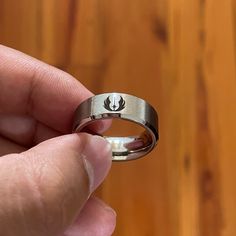 someone is holding their wedding ring in front of the camera on a wooden table with wood flooring