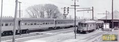 two trains on tracks next to each other in an old time train station with snow and power lines