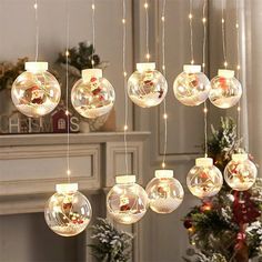 christmas ornaments hanging from the ceiling in front of a fire place and decorated with lights