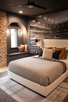 a bedroom with a large bed and a brick wall in the background, along with a painting on the wall