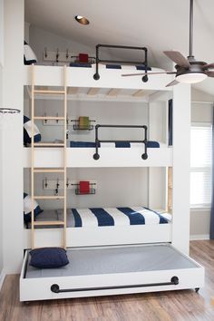 a bunk bed with ladders is in the middle of a room that has hardwood floors and white walls