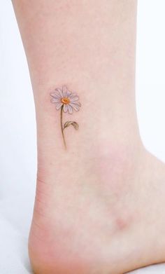 a small flower tattoo on the ankle is shown in this image, it looks like a single daisy