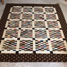 a quilt is laying on the floor with it's border made out of squares