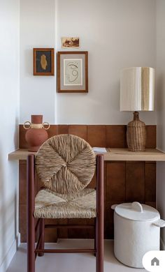 a chair sitting in front of a desk with pictures on the wall above it and a lamp next to it