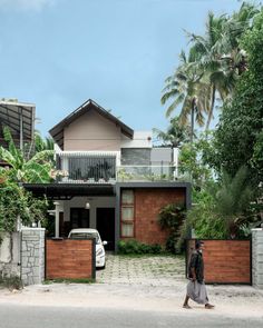 a man walking down the street in front of a house