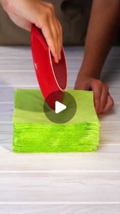 a person is using a red paddle on top of some green napkins to clean the table