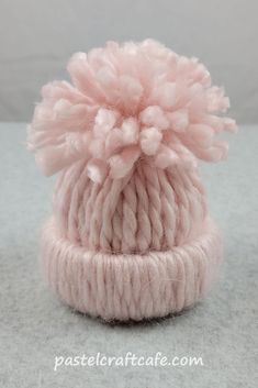 a pink knitted hat with pom - poms