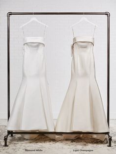 two white dresses on display in front of a brick wall