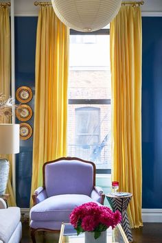 a living room with blue walls and yellow curtains