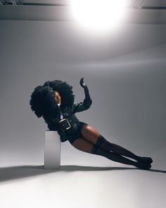 a woman in black is posing on a white pedestal