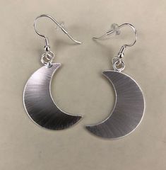 I've designed a pair of crescent moon earrings, 1 1/8 inches each in size, with dangling ear hook wires. The set is completely handmade in sterling silver. Inspired by Stevie Nicks, I wanted to fabricate matching earrings to the moon pendant and as this was for a customer request, I thought, what a grand idea! I can offer a 24K gold plating option that I will include in the drop down menu at checkout! The last image is to show the crescent moon necklace. Please convo for any questions! Allow me Celestial Moon Phase Moon Earrings, Silver Moon Phase Drop Earrings, Elegant Half Moon Earrings With Moon Charm, Celestial Half Moon Earrings With Moon Phase Detail, Elegant Crescent Moon Charm Earrings, Elegant Adjustable Moon Shaped Earrings, Metal Moon-shaped Jewelry With Matching Earrings, Elegant Nickel-free Moon Shaped Earrings, Elegant Nickel-free Moon-shaped Earrings