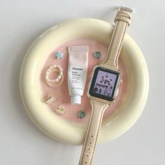 an apple watch sitting on top of a white plate next to a tube of cream