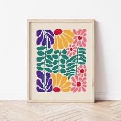 a cross stitch pattern with colorful flowers in a frame on the floor next to a wall