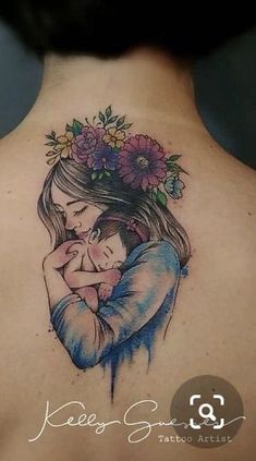 a woman with a tattoo on her back holding a baby