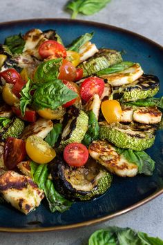 a blue plate filled with grilled vegetables on top of a table