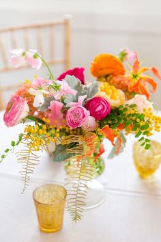 a vase filled with flowers sitting on top of a table next to a glass cup