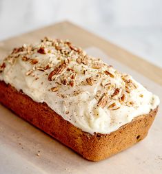 a loaf of cake with white frosting and nuts on top