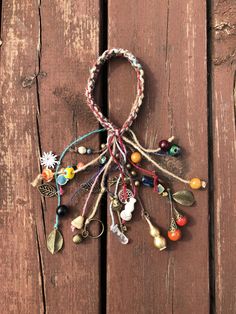 an assortment of beads and charms hanging on a wooden surface with wood planks in the background