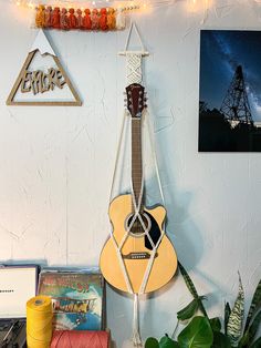 an acoustic guitar hanging on the wall next to some books and other items in front of it