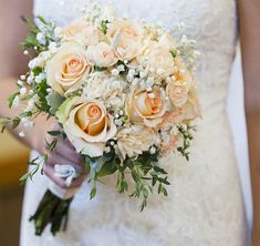 a bridal holding a bouquet of white and peach flowers