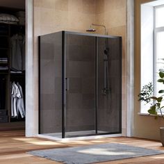 a walk in shower sitting on top of a wooden floor next to a potted plant