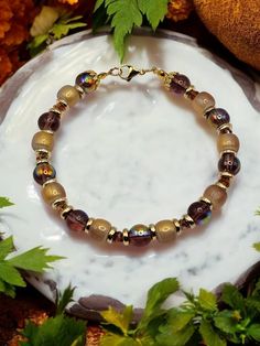 Imagine strolling through a sun-drenched marketplace, where the rich aromas of spices mingle with the vibrant colors of exotic treasures. This bracelet and earring set captures the essence of such a scene, blending together glass beads in luxurious shades of deep brown, warm taupe, and gleaming gold accents. Each bead is a reflection of earth's embrace, evoking the warmth of sun-kissed sands and the richness of ancient spices. Interwoven amidst the beads are subtle hints of golden accents, like rays of sunlight dancing upon the desert sands, adding a touch of opulence and refinement to the set. The combination of colors and textures creates a harmonious balance, invoking a sense of timeless elegance and sophistication. This lovely bracelet is 7 and 1/2 inches in diameter. All of my jewelry Gold Czech Glass Beaded Bracelets, Spiritual Gold Bracelets With Czech Glass, Spiritual Gold Bracelet With Czech Glass, Brown Czech Glass Jewelry Bracelet, Hand-strung Gold Jewelry With Czech Glass, Hand-strung Gold Czech Glass Jewelry, Gold Czech Glass Jewelry, Hand-strung, Desert Sand, Deep Brown