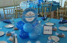 a table with blue and white plates, silverware and balloons