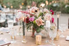 the table is set with silverware and flowers in glass vases, plates and napkins