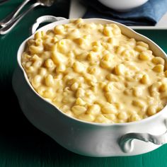 a white bowl filled with macaroni and cheese on top of a green table