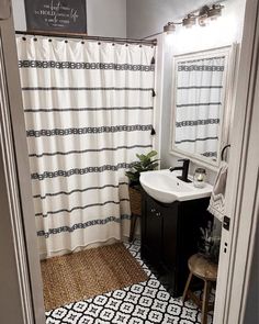 a bathroom with a white sink and black and white shower curtain next to a mirror