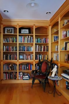 a room filled with lots of books and furniture next to a wall full of shelves