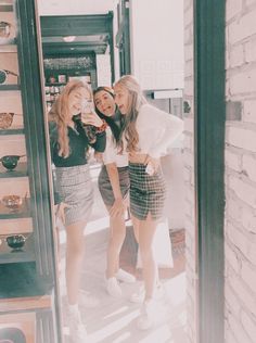 three young women standing in front of a mirror