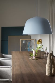 a wooden table topped with a lamp and vase filled with flowers next to a window