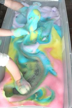 a child is playing with colored sand in a plastic container