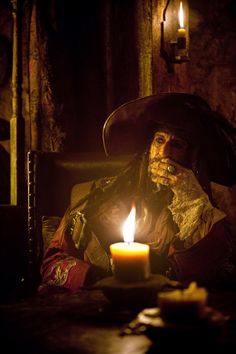 a man dressed as a pirate holding a lit candle