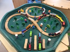 a toy train set with cars and tracks in a green tray on top of a table