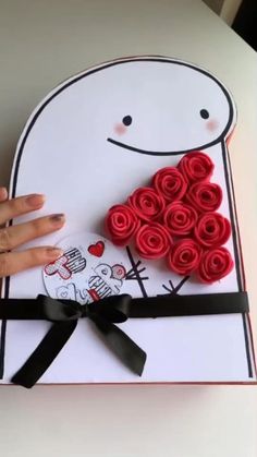 a hand is holding a box with roses in the shape of a man's face