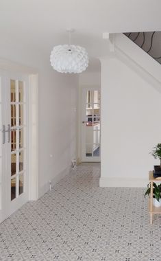 an empty room with white walls and flooring next to a stair case that leads up to the second floor