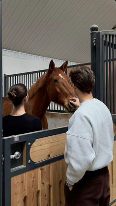 a man and woman standing next to a brown horse