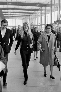 black and white photograph of people walking through an airport terminal, with one woman in the foreground