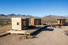 two tiny houses in the desert with mountains in the background